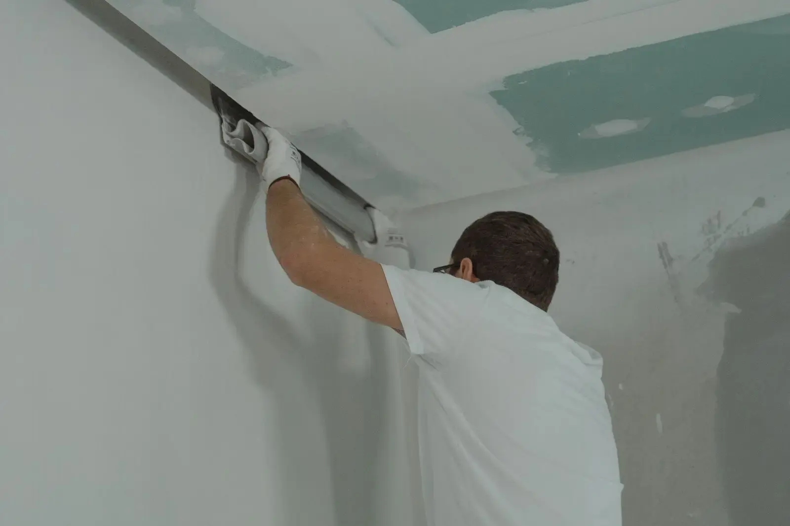 Worker finishing new drywall on a wall